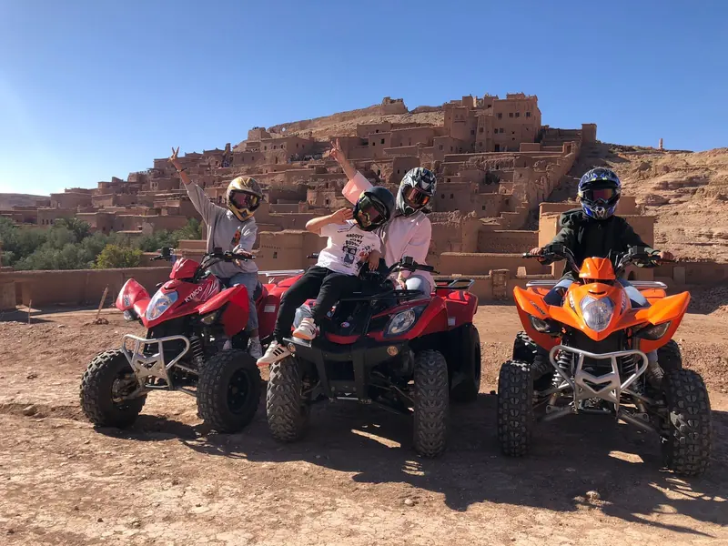 Quad riders posing with the ksar of Ait Ben Haddou behind them