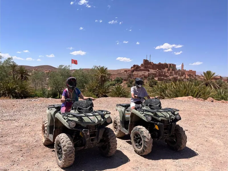 Two quads on a rocky plateau facing Ait Ben Haddou
