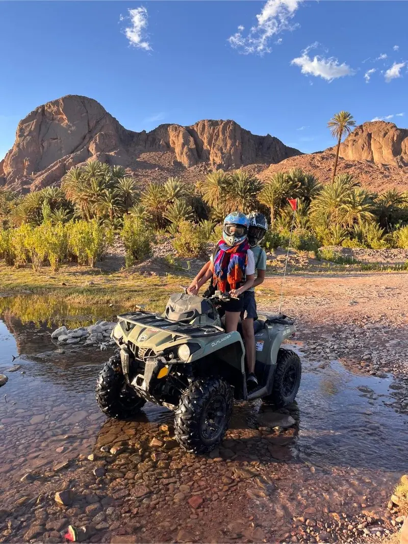 A quad driving through shallow water in the Fint oasis