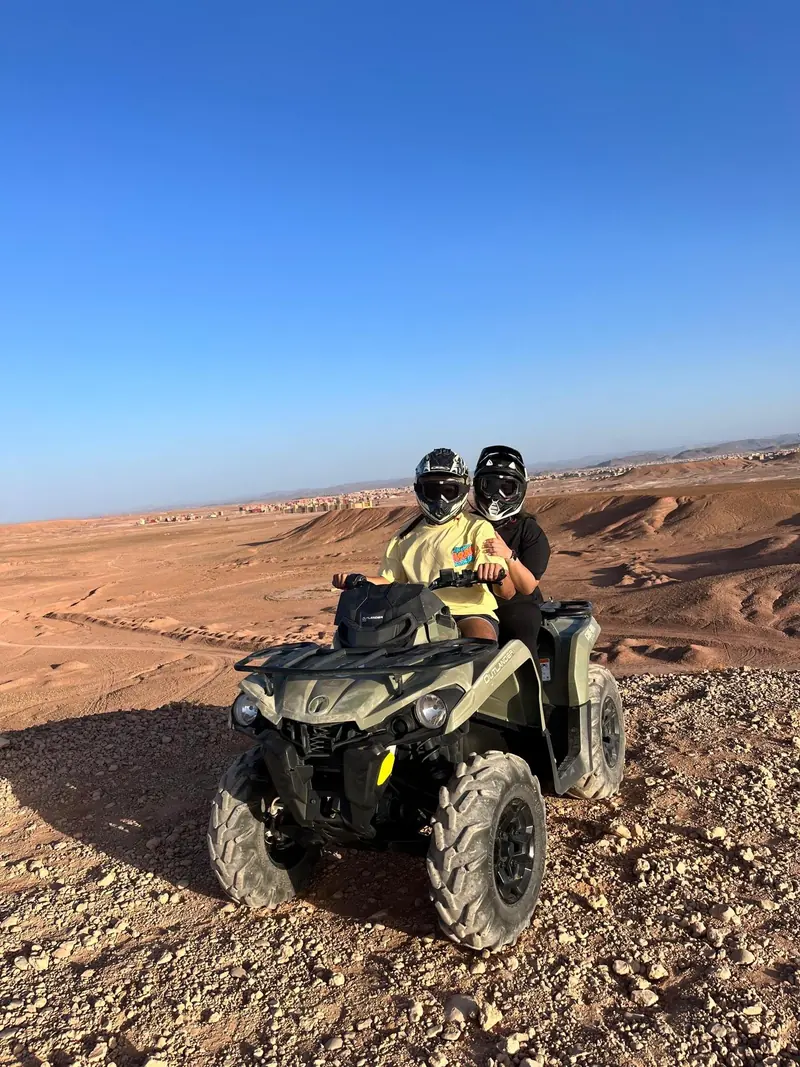 Two riders on a quad crossing an open stony plateau