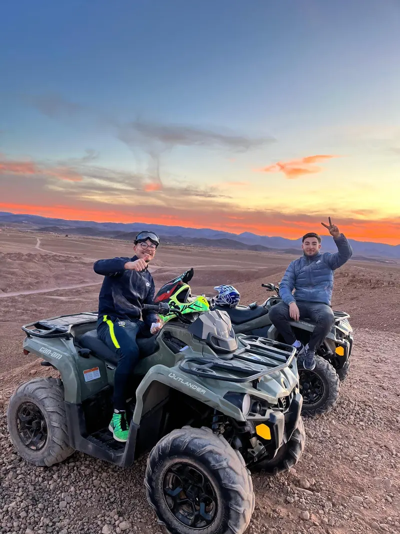 Riders celebrating on a quad at sunset in the desert